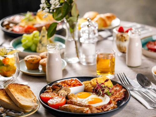 a table with plates of breakfast food on it at The Harlow Hotel By AccorHotels in Harlow