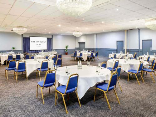 a conference room with white tables and blue chairs at The Harlow Hotel By AccorHotels in Harlow