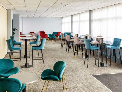 a waiting room with chairs and tables and tables at The Harlow Hotel By AccorHotels in Harlow