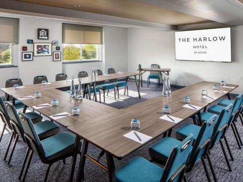 a conference room with long tables and blue chairs at The Harlow Hotel By AccorHotels in Harlow