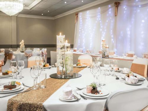 a banquet room with white tables and chairs with candles at The Harlow Hotel By AccorHotels in Harlow
