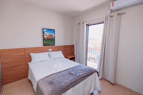a bedroom with a bed and a large window at Sttudio One in Araxá