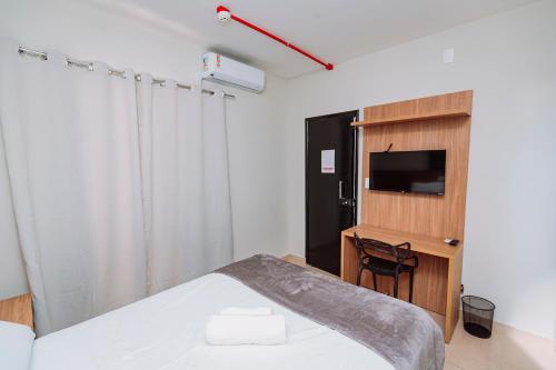 a bedroom with a bed and a tv and a chair at Sttudio One in Araxá