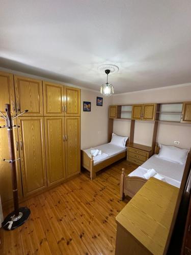 a room with two beds and wooden cabinets and a table at Canka Guest House in Përmet