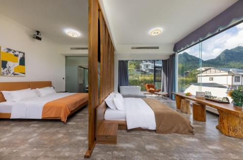 a bedroom with two beds and a large window at Zhangjiajie Flowers Valley,Watching Sunrise Cloud Sea, enjoying an infinity pool, free Chinese and Western breakfast, and free shuttle service to the entrance of the National Forest Park in Zhangjiajie