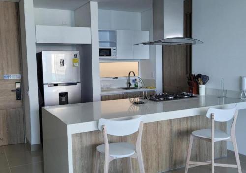 a kitchen with a counter with two white stools at RESERVA DEL MAR - Playa Salguero - By INMOBILIARIA VS in Santa Marta