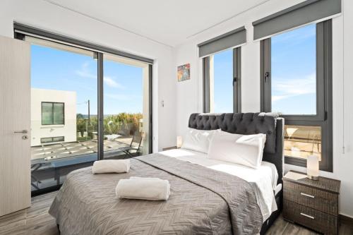 ein Schlafzimmer mit großem Bett und großen Fenstern in der Unterkunft Villa Alassia 16 by Ezoria Villas in Paralimni