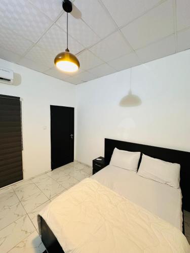 a bedroom with a white bed and a black door at Résidence Océane in Godomey