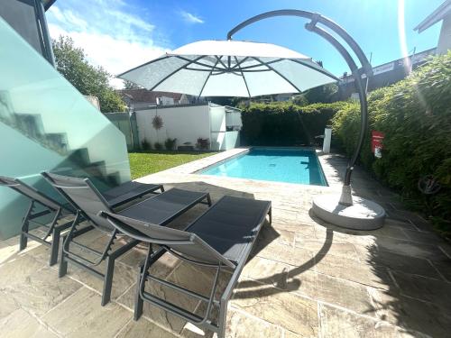 a pair of chairs and an umbrella next to a pool at Gästehaus Sommertal, eigener Parkplatz, 800m zum Bodensee, 300m zur Altstadt in Meersburg