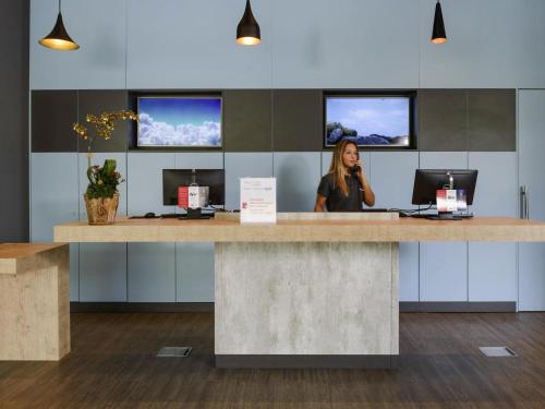 a woman standing at a reception desk in an office at ibis Itatiba in Itatiba