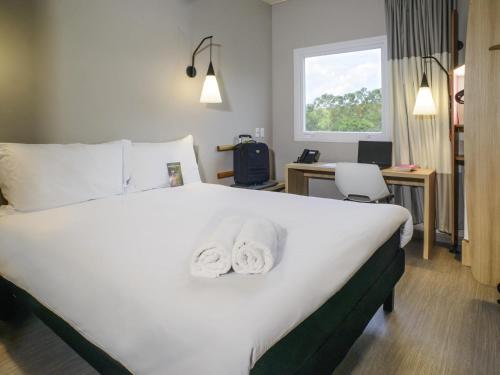 a hotel room with a bed with towels on it at ibis Itatiba in Itatiba