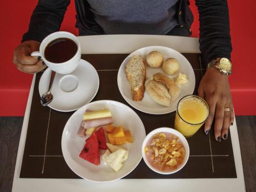 a person holding a cup of coffee and a tray of food at ibis Itatiba in Itatiba