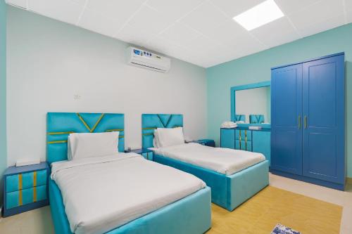 a bedroom with two beds and blue cabinets at The Sunshine Farm by Al Dana Paradise Luxury 6BR Secluded Nature Mountains in Khor Fakkan