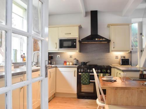 a kitchen with white cabinets and a stove top oven at Hillside Cottage in Glossop