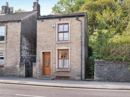 a brick house with a wooden door on a street at Hillside Cottage in Glossop
