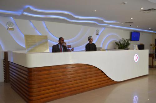 two men standing at a counter in a lobby at Ramee Dream Resort in Seeb