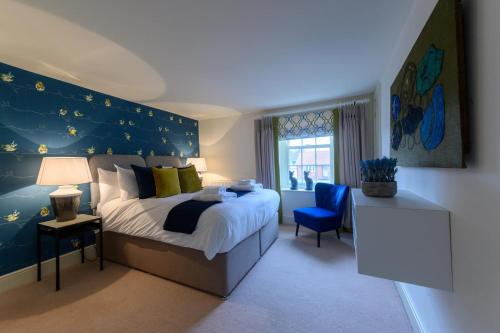 a bedroom with a large bed and a blue wall at Vine Cottage in Blakeney