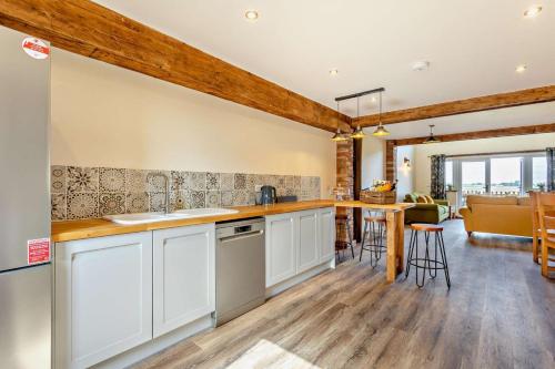 a kitchen with white cabinets and a dining room at Monks Barn in Upwell