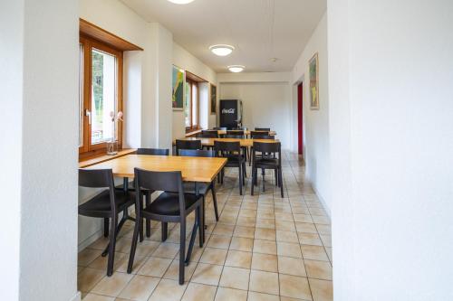 a dining room with wooden tables and black chairs at Delémont Youth Hostel in Delémont