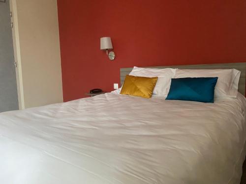 a white bed with three pillows on top of it at Hôtel de Flandre in Compiègne