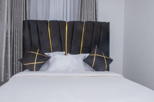 a bed with a black headboard and white pillows at Kayla Suites in Busia