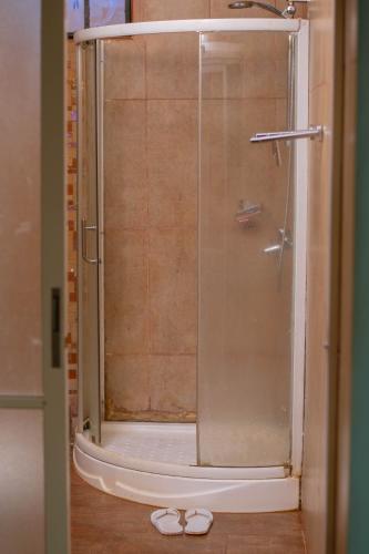 a shower with a glass door and a pair of shoes at Hotel Quill in Busia
