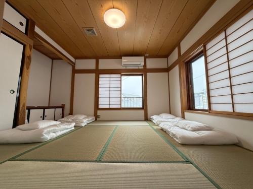 a room with four beds in a room with windows at E KI house ski school in Yuzawa