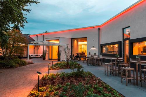 a house with a patio with tables and chairs at Mintrops Land Hotel Burgaltendorf in Essen