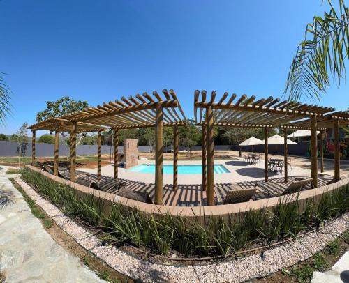 a pool with chairs and a wooden pergola at Chácara Reserva do Cerrado in Cavalcante