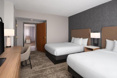 a hotel room with two beds and a desk at Embassy Suites by Hilton at Hot Springs Convention Center in Hot Springs