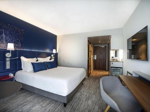 a bedroom with a large white bed and a blue wall at Hôtel Mercure Toulon La Seyne-Sur-Mer in La Seyne-sur-Mer