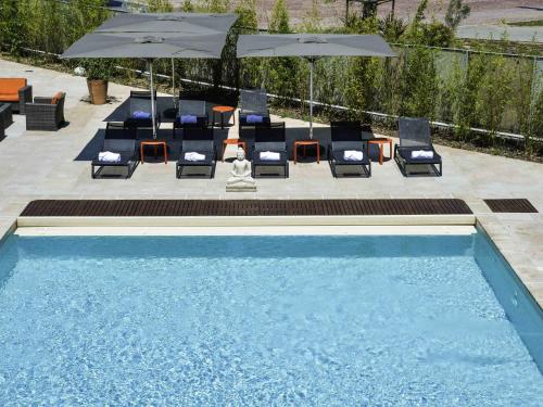 a swimming pool with lounge chairs and umbrellas at Hôtel Mercure Toulon La Seyne-Sur-Mer in La Seyne-sur-Mer