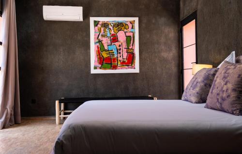 a bedroom with a bed and a painting on the wall at CASA MISASHA nature, calme, bio et vos repas préparés par notre cuisinière in Essaouira