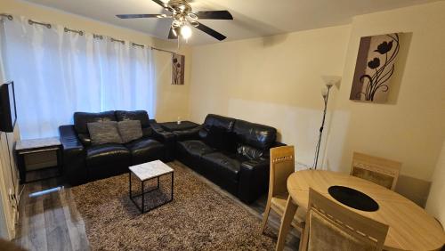 a living room with a black leather couch and a table at Charlotte Apartment in Aberdeen