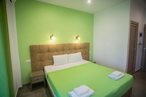 a green bedroom with a bed with two towels on it at Studios Nopi-Zoi in Skiathos Town