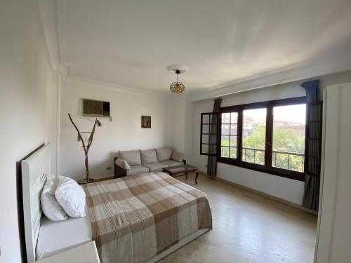 a bedroom with a bed and a couch and a window at Villa Maadi 35 - R 301 - Street View Room in Cairo