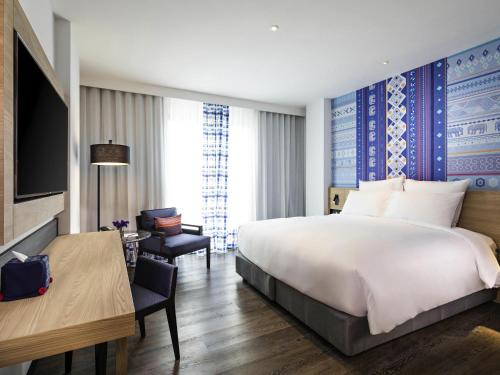 a hotel room with a large bed and a desk at Novotel Chiangmai Nimman Journeyhub in Chiang Mai