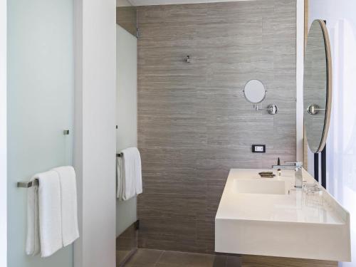 a bathroom with a white sink and a mirror at Novotel Chiangmai Nimman Journeyhub in Chiang Mai