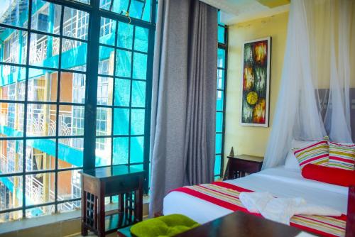 a hotel room with two beds and a large window at Hotel Quill in Busia