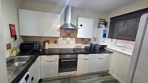 a kitchen with white cabinets and a sink at Charlotte Apartment in Aberdeen