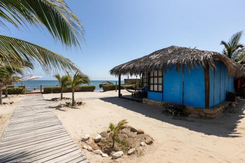 a blue hut on the beach with a pathway at Hoja de Palma Bungalows in Canoas De Punta Sal