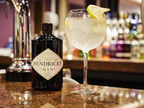 a drink in a glass next to a bottle of alcohol at Mercure St Helens in Saint Helens
