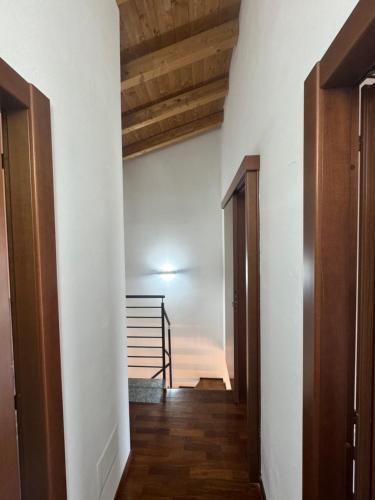 a hallway with white walls and wooden floors and a staircase at Entro le mura in Piacenza