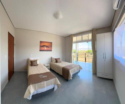 a bedroom with two beds and a large window at Chácara Reserva do Cerrado in Cavalcante