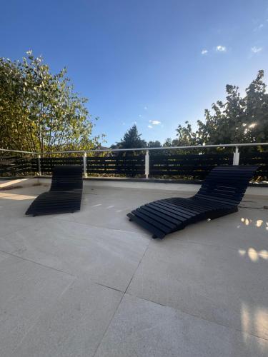 two black benches sitting on a sidewalk next to a fence at Avala Villa With Indoor Pool & Spa in Vrčin