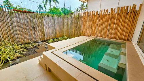 a swimming pool in front of a wooden fence at ETHER Marari Beachfront in Mararikulam