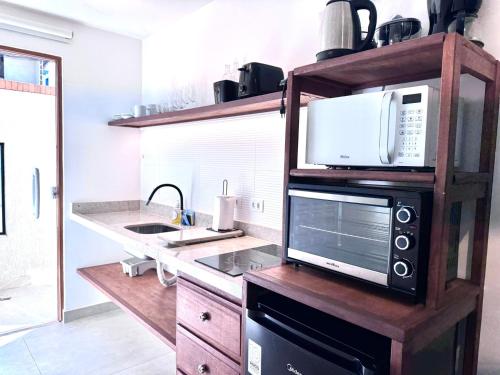 a kitchen with a microwave oven and a sink at Bella Buzios Apartamentos in Búzios