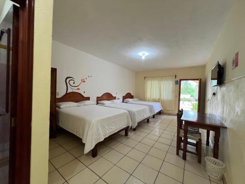a bedroom with two beds and a table and a television at Hotel y Restaurante Villas Del Sol Jalpan de Serra in Jalpan