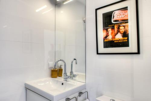 ein Badezimmer mit einem Waschbecken und einem Filmplakat an der Wand in der Unterkunft Porto Cinema Apartments in Porto