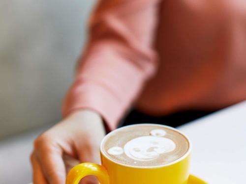 a person sitting at a table with a cup of coffee at ibis Styles East Perth in Perth